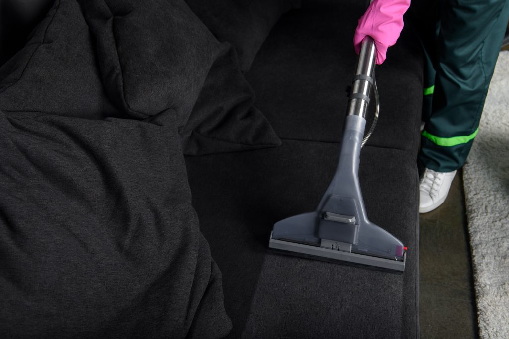 cropped shot of person cleaning furniture with vacuum cleaner, upholstery cleaning concept